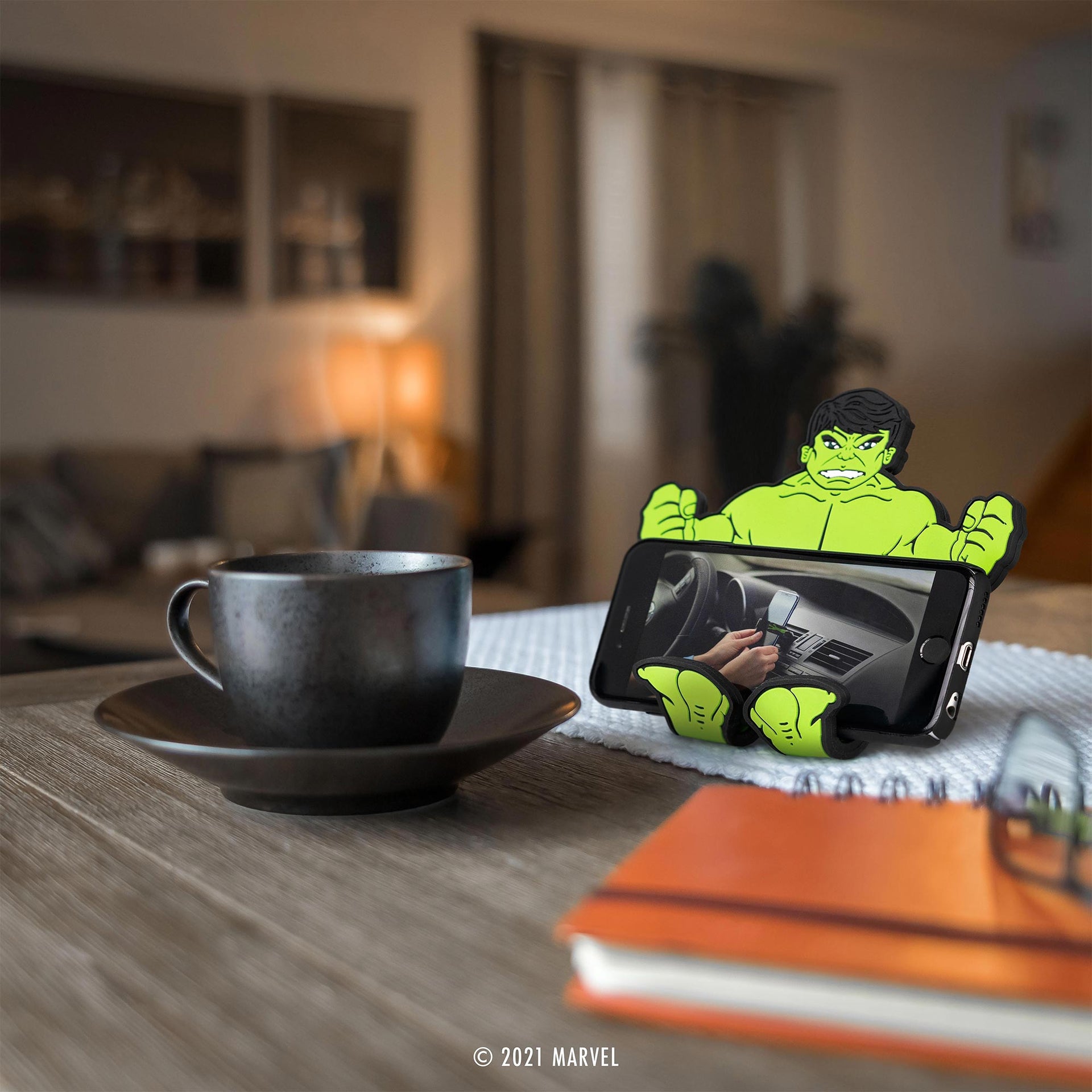 Image of Marvel Comics Hulk Hug Buddy holding a cell phone beside a cup of coffee while sitting on a kitchen table