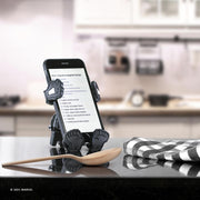 Image of Marvel Comics Venom Hug Buddy resting on its vent clip on top of a kitchen counter displaying a recipe on the phone screen that its holding