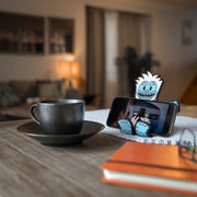 Image of the Yeti Hug Buddy holding a cellphone sitting on a kitchen table beside a warm cup of coffee or tea