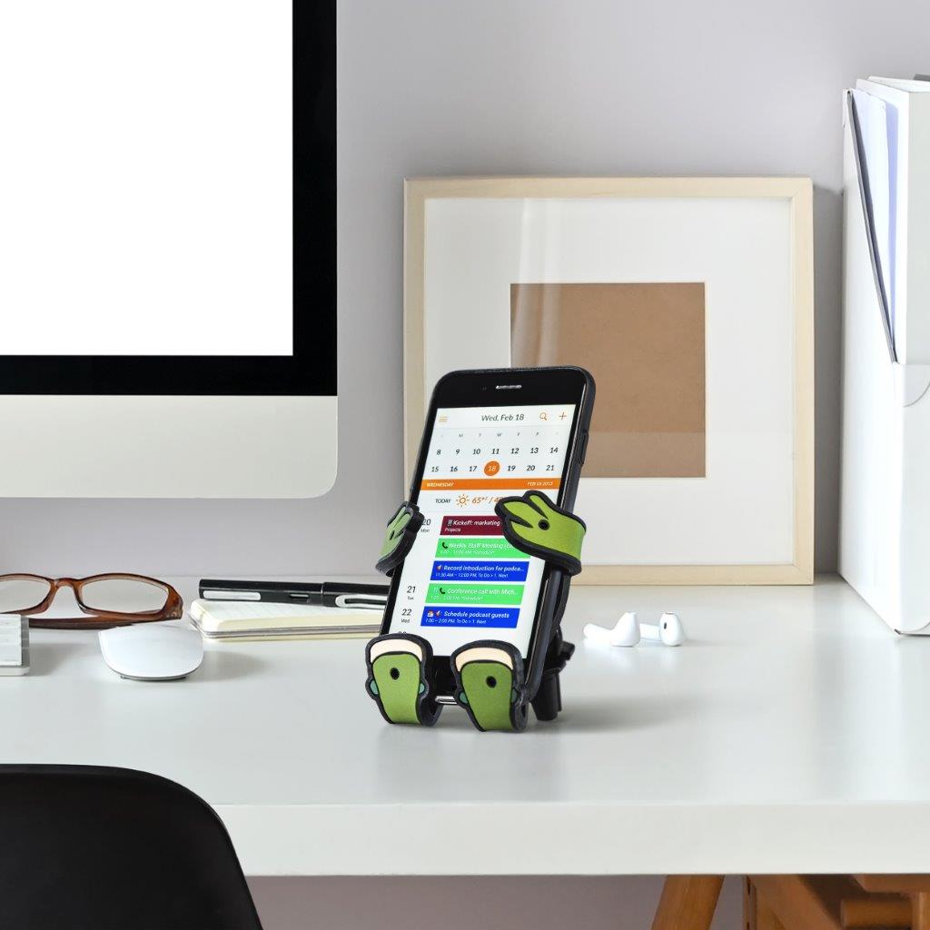 Image of Shellebrity the Turtle Hug Buddy holding a cell phone with a calendar on the screen, on top of a home office desk