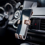 Image of Pug the dog Hug Buddy attached to a car air vent holding a cell-phone