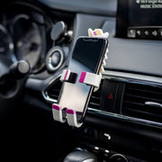 Image of Pukeycorn the unicorn Hug Buddy holding a cell phone attached to a car air vent