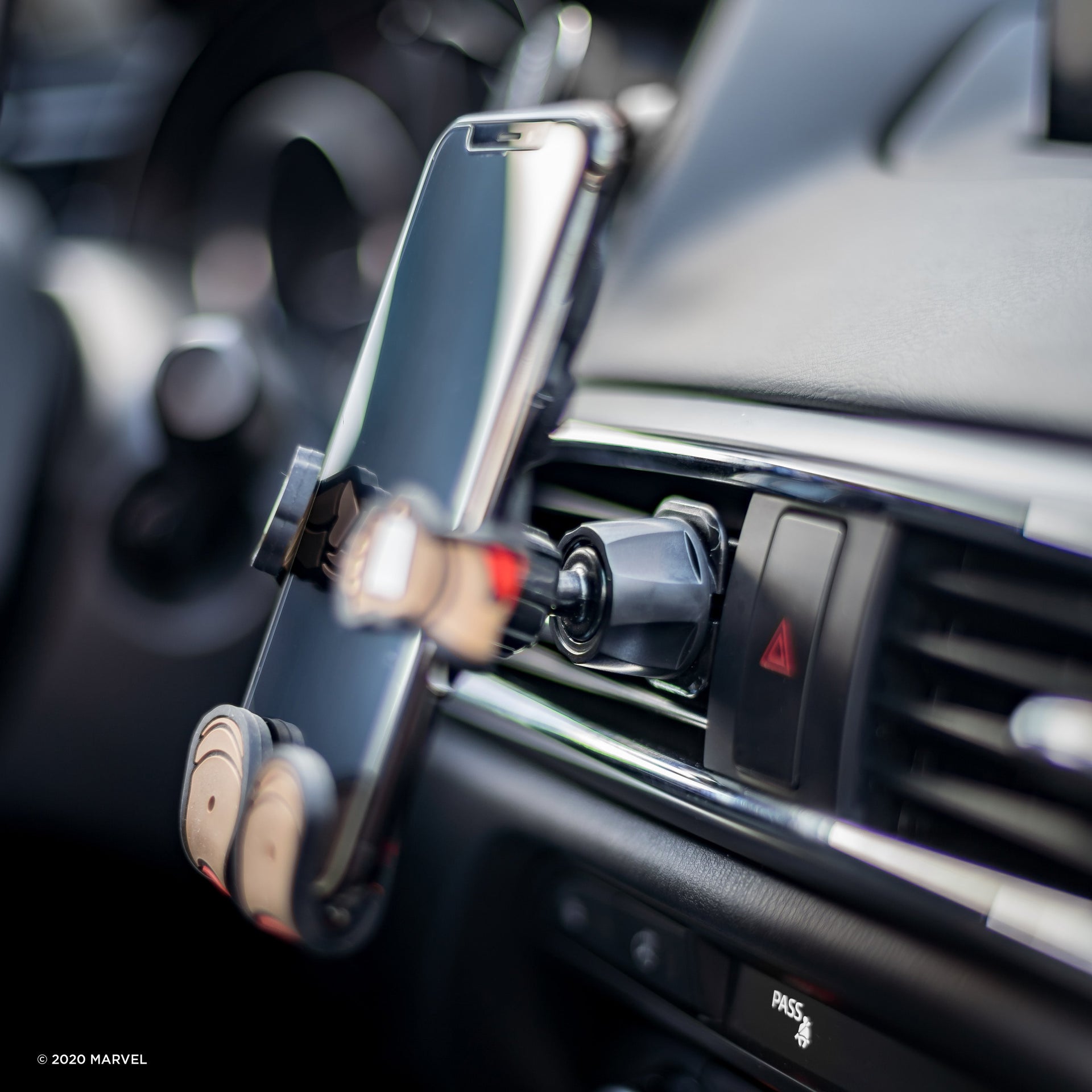 Image of Marvel Captain America Hug Buddy holding a phone, attached to a car air vent, close-up on the vent clip