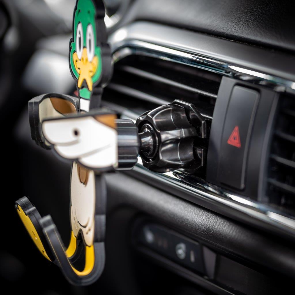 Image of Crumbs the duck Hug Buddy attached to a car air vent with arms and legs folded inward ready to hold onto a smart device or cell-phone during your next journey, with a close-up on the vent clip attached to the air vent of the vehicle