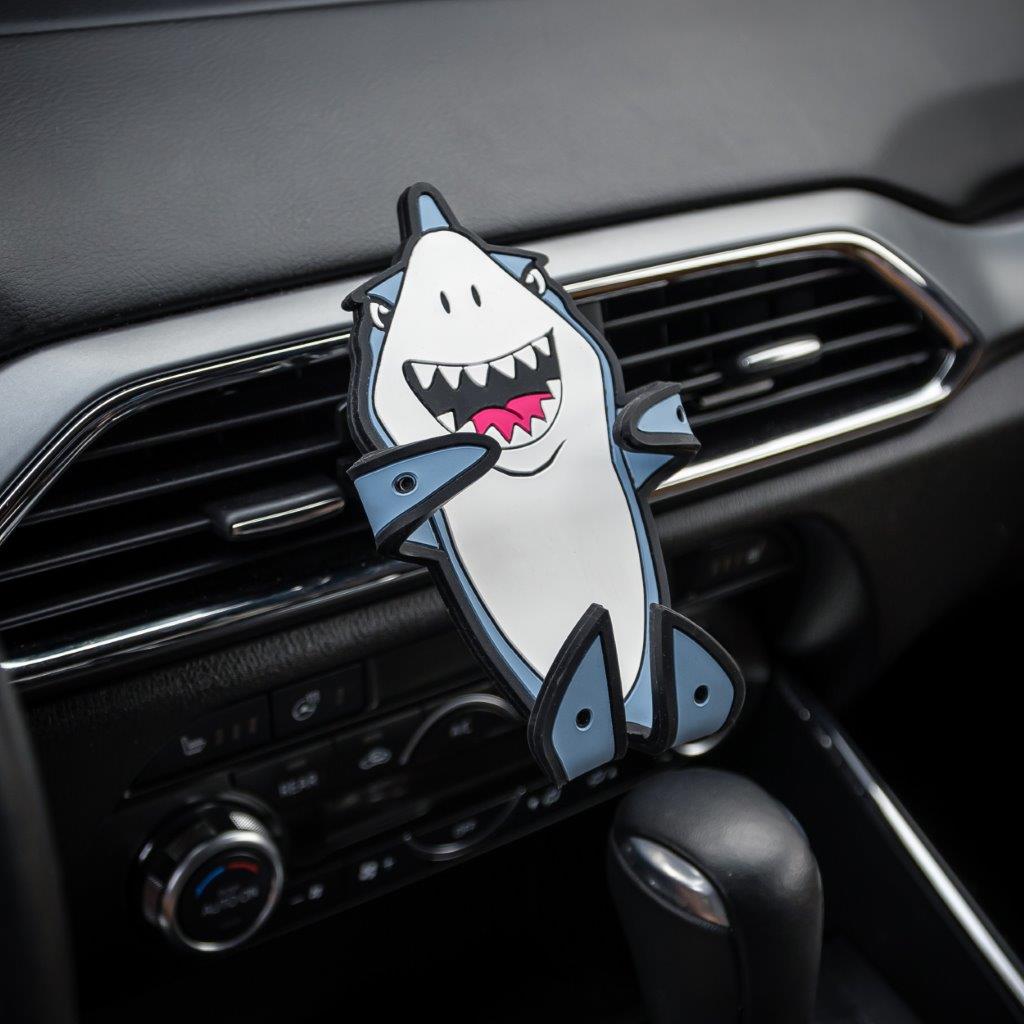 Image of Jaws the Shark Hug Buddy attached to a vehicle air vent with arms and legs folded in the closed position ready to grasp a phone or other smart device