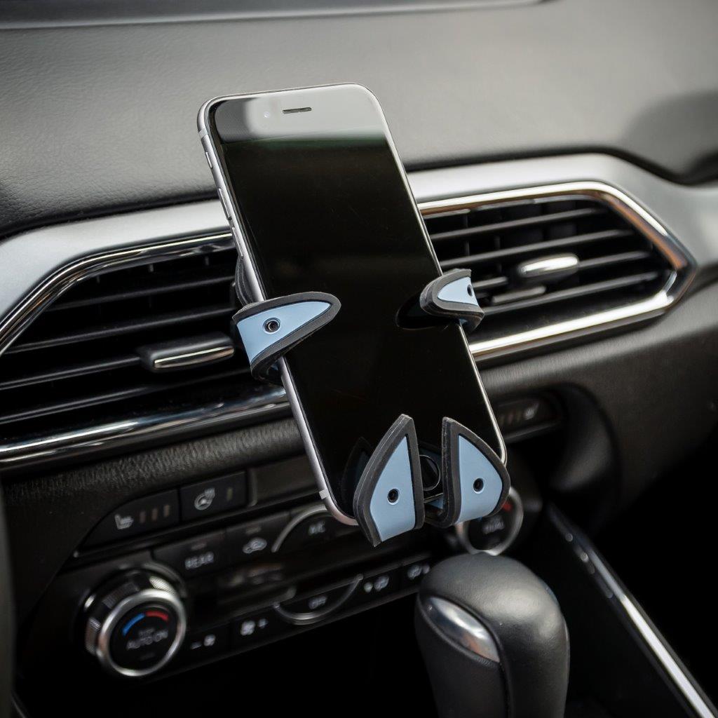 Image of Jaws the Shark Hug Buddy holding a cell phone attached to a car air vent with its vent clip