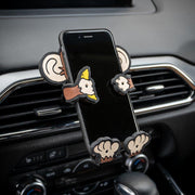 Image of Monkey Hug Buddy attached to a car air vent, holding a cell-phone.