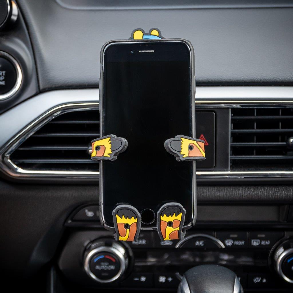 Image of Shorty the Giraffe Hug Buddy attached to a car air vent holding a cell phone