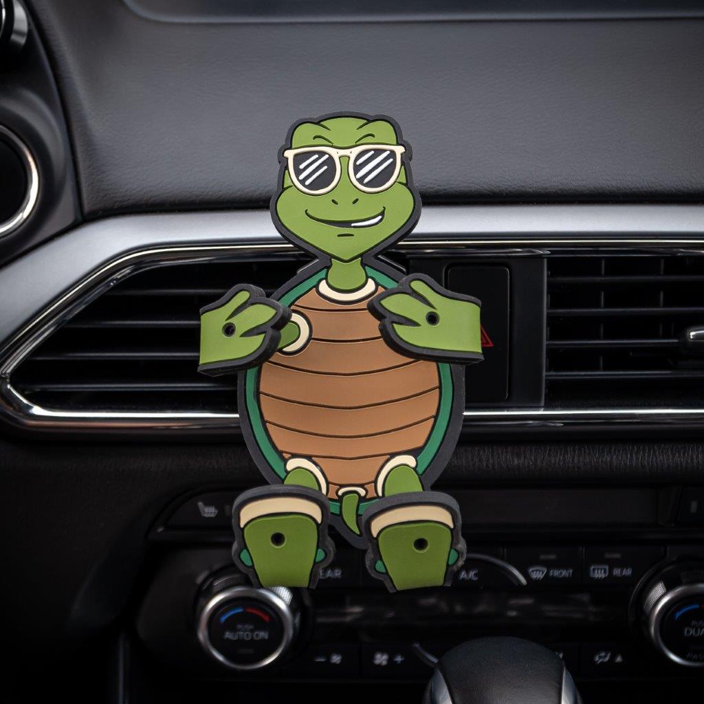 Image of Shellebrity the Turtle Hug Buddy attached to a car air vent with arms and legs in the closed folded position, with no cell-phone in its grasp