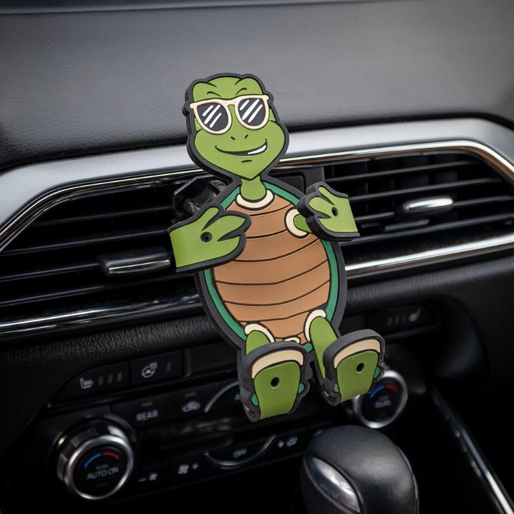 Image of Shellebrity the Turtle Hug Buddy attached to a car air vent with arms and legs in the closed folded position, with no cell-phone in its grasp