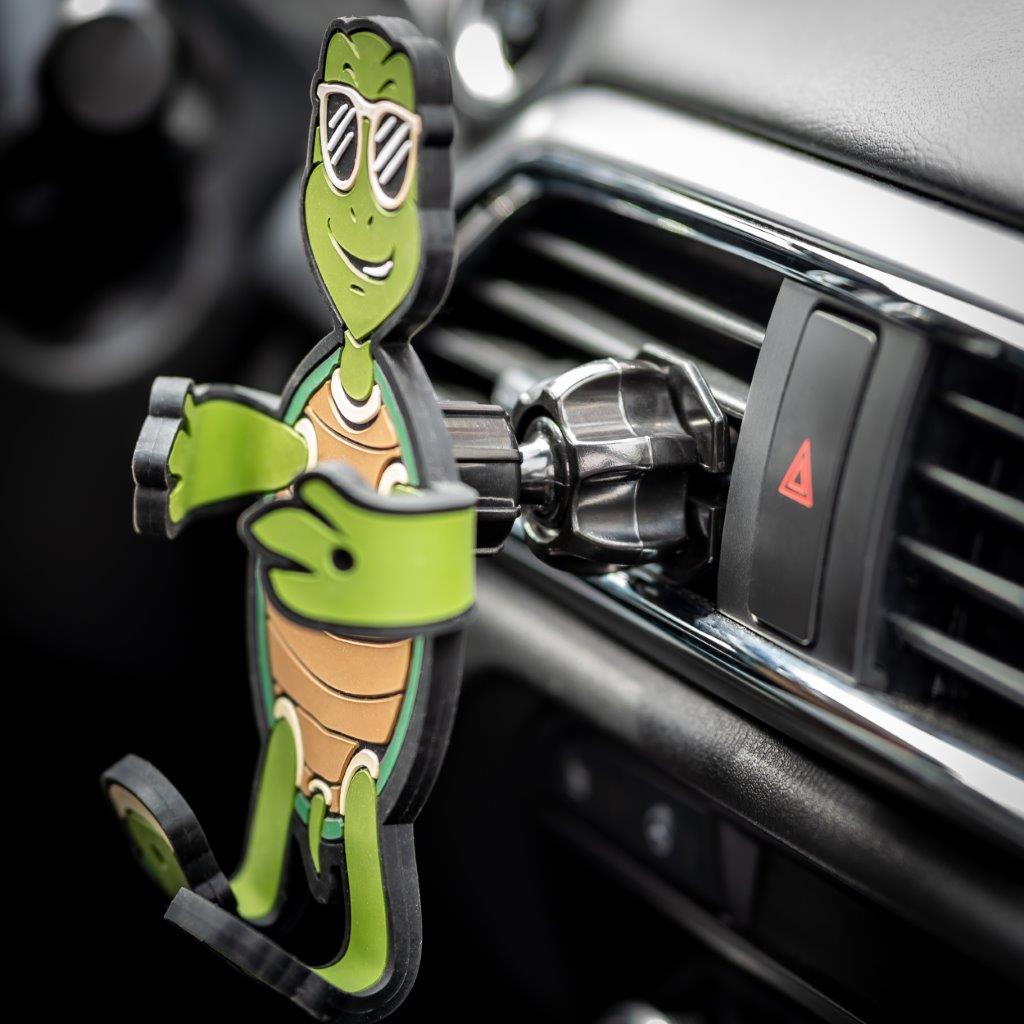 Image of Shellebrity the Turtle Hug Buddy attached to a car air vent with arms and legs in the closed folded position, with no cell-phone in its grasp. Close-up image of the vent clip.