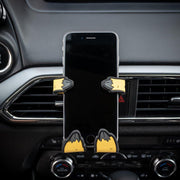 Image of Relaxa the Llama Hug Buddy attached to a vehicle air vent holding a cell phone