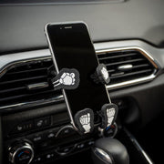 Image of Bones the Skeleton Hug Buddy attached to a car air vent holding a smart phone