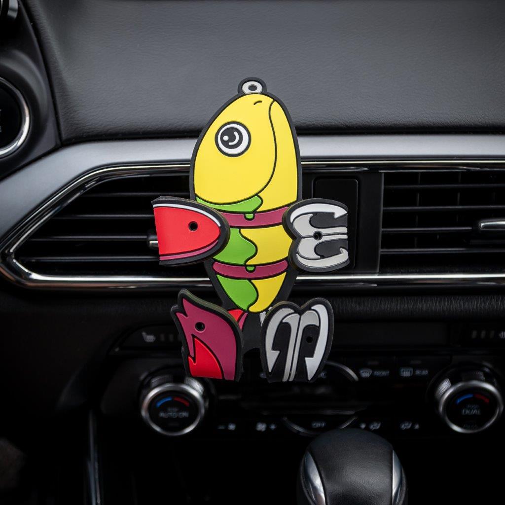 Image of Shaky the fish bait Hug Buddy attached to a car air vent with arms and legs folded, ready to hold your phone on your next adventure