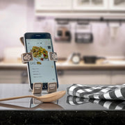 Image of Pug the dog Hug Buddy holding a cell phone displaying a recipe on the screen, while resting on its vent clip on top of a kitchen counter
