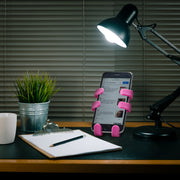 Image of OG Pink Hug Buddy holding a cell phone while sitting on a home office desk