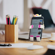 Image of Pukeycorn the unicorn Hug Buddy holding a cell phone while sitting on a home office desk